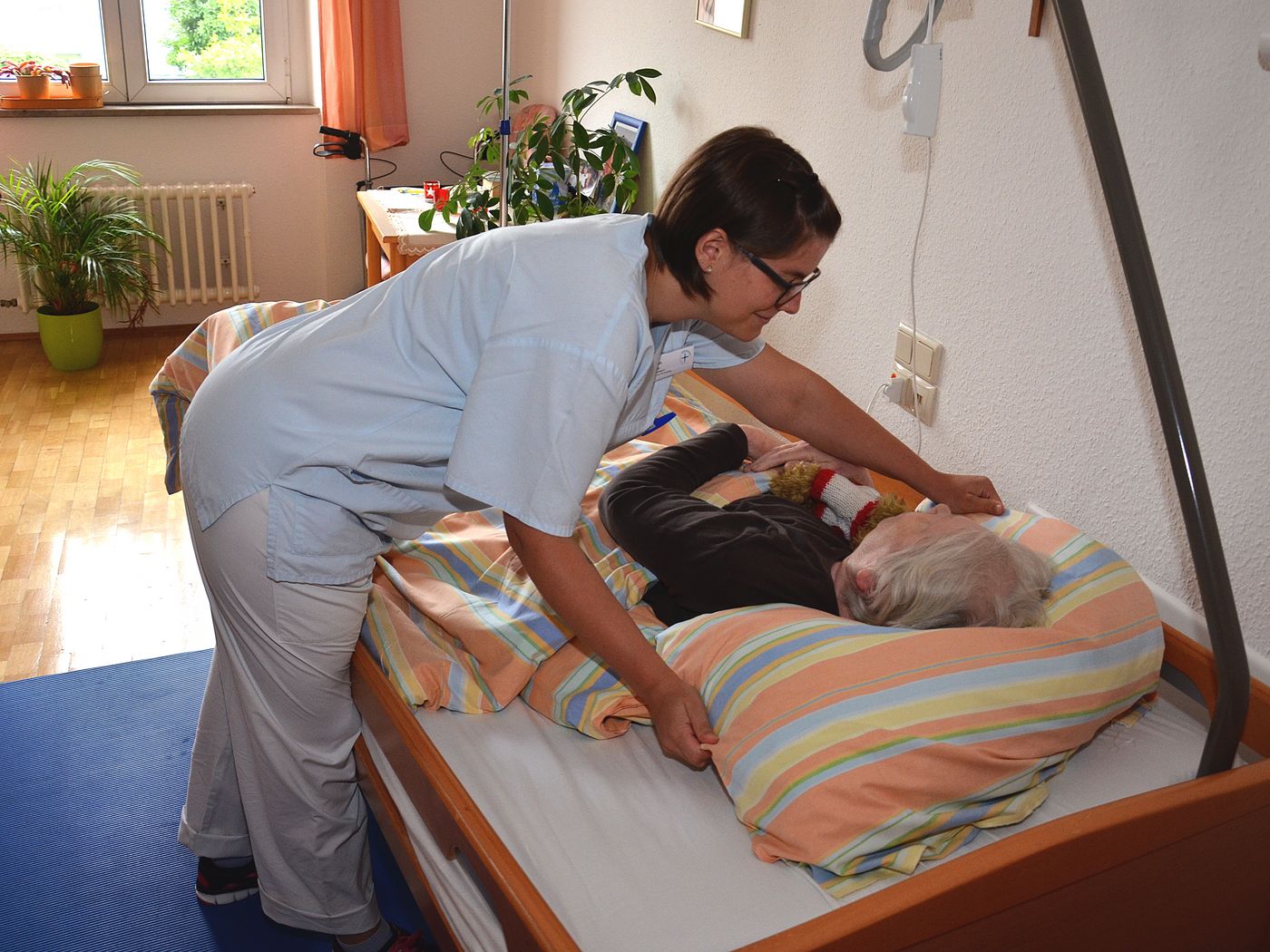 Pflegerin überzieht ein Patientenbett