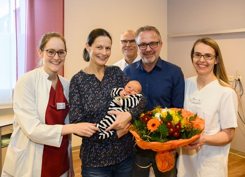 Eltern und Baby mit Geburtshilfeteam