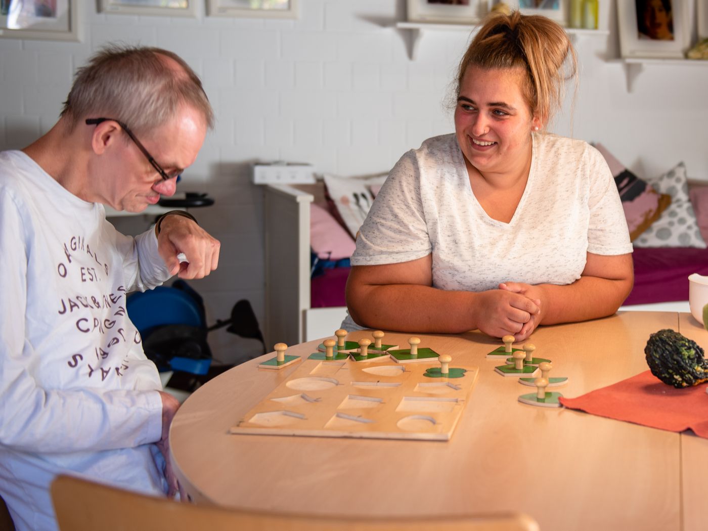 Betreuerin spielt mit Menschen mit Behinderung am Tisch