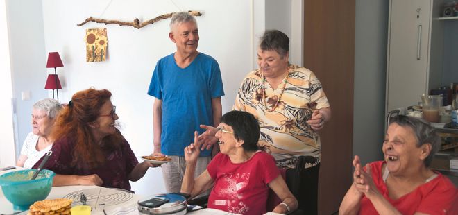 Gruppe sitzt am Tisch und backt Waffeln