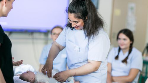 Schülerin übt Babywickeln