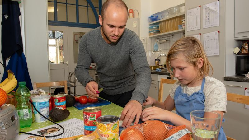 Betreuer und Junge beim Kochen