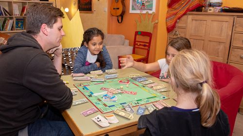 Erzieher und Kinder beim Monopoly spielen