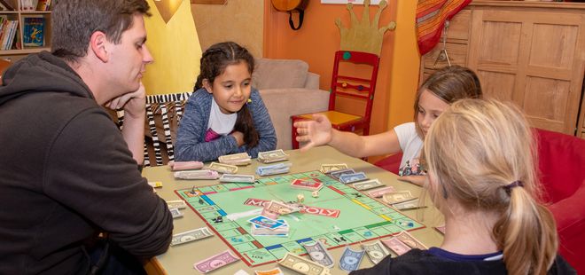 Erzieher und Kinder beim Monopoly spielen