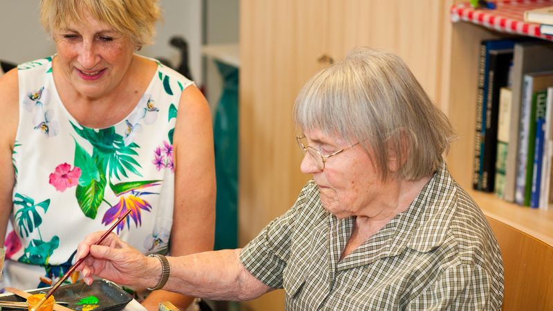 Seniorin und Lehrerin beim Malen