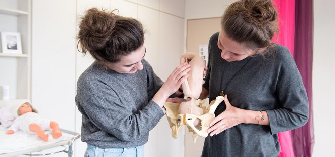 Zwei Hebammenschülerinnen mit Übungsbaby