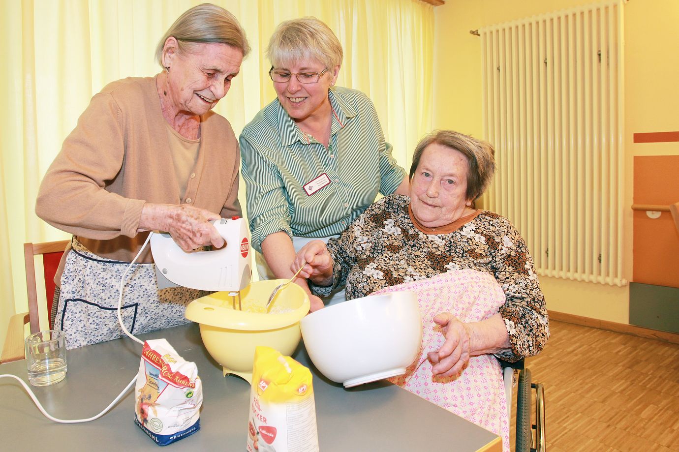 Mitarbeiterin und Bewohnerinnen beim Backen