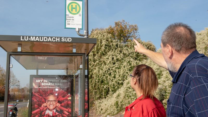 Ehrenamtlicher zeigt Frau mit Behinderung Bushaltestelle