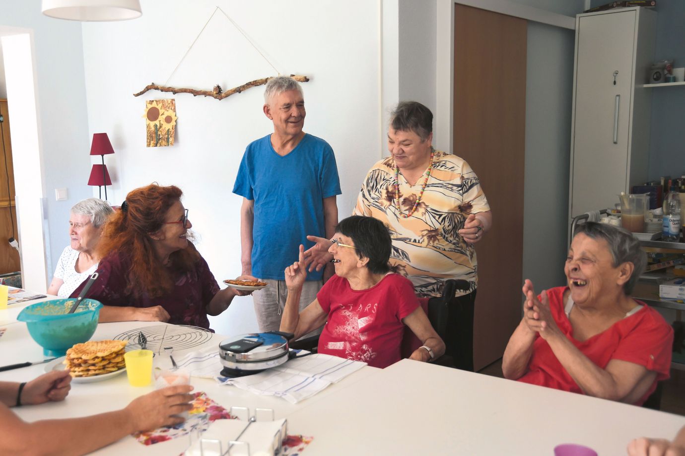 Gruppe sitzt am Tisch und backt Waffeln