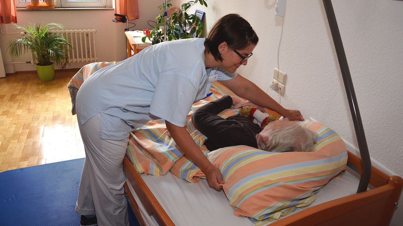 Pflegerin überzieht ein Patientenbett