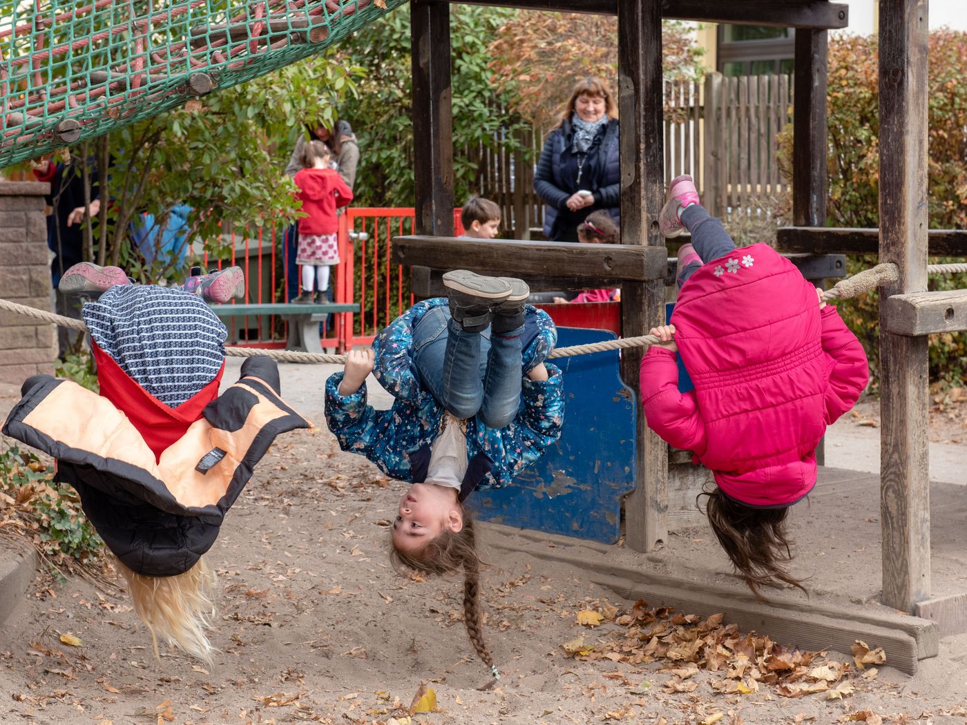 3 Mädchen turnen am Seil auf Spielplatz