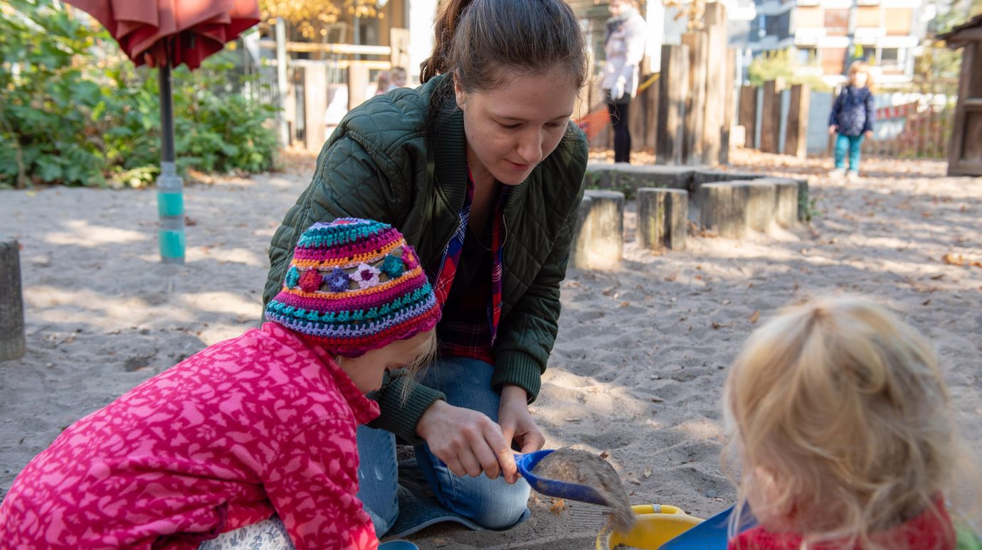 Erzieherin mit zwei Kindern im Sandkasten