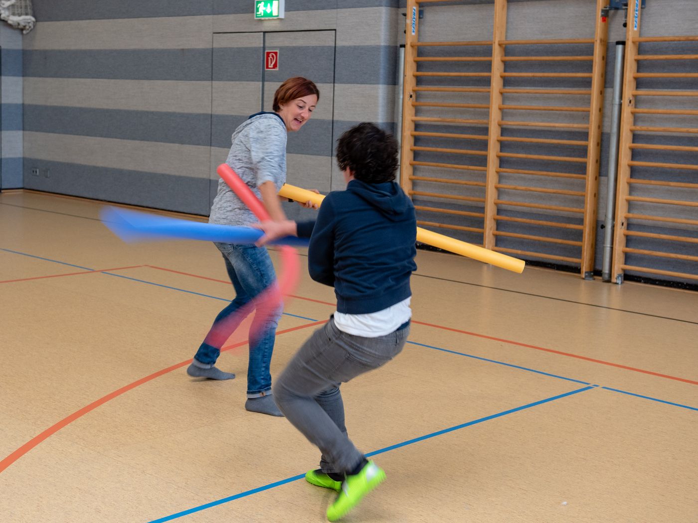 Betreuerin und Schüler duellieren sich mit Schwimmnudel