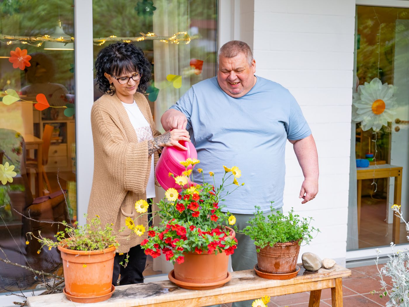eine Frau und ein Mann gießen Blumen